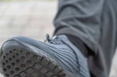 Mavi spor ayakkabılı erkek bacaklarına yakın çekim. Açık hava bankında oturan yetişkin bir erkeğin bacakları. Gündüz vakti. Seçici odak.