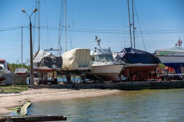 İskele boyunca kaygan yola bir grup yat monte edildi. Zevk tekneleri ve yatlar korunuyor. Gündüz vakti. Ukrayna, Mykolaiv - 05 07 2022