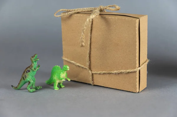 Hnědá Lepenková Krabice Miniatury Dvou Dinosaurů Šedém Pozadí Zadních Nohách — Stock fotografie