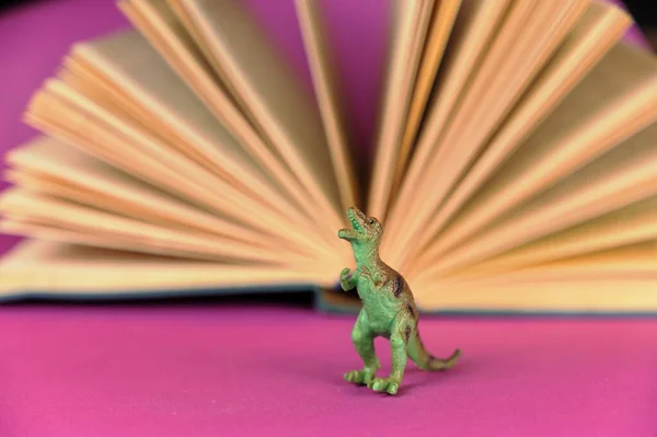 Dinosaurus Open Boek Tegen Paarse Achtergrond Groene Plastic Miniatuur Van — Stockfoto