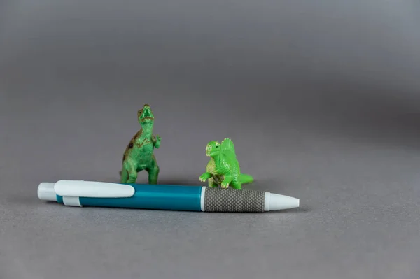 Dos Miniaturas Dinosaurios Bolígrafo Sobre Fondo Gris Pequeñas Figuras Verdes — Foto de Stock