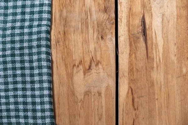 Yeşil kareli bir kumaş, ahşap bir zemine dayanır. Kaba tahtalara ya da mutfak masasına havlu ya da peçete..