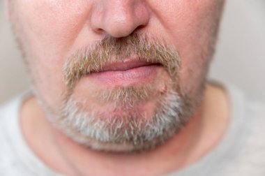 Adamın yüzünün alt kısmından. Sakallı, olgun bir adam. Sakallı ve bıyıklı gri saçlı. Adamın suratının alt kısmı. Seçici odak.