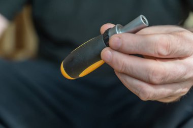 Tornavida tutan olgun bir adamın eli. Değiştirilebilir bitlerle el aracı.