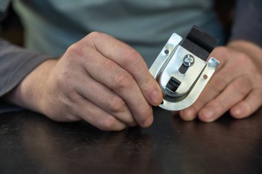 Yetişkin bir erkek, sürgülü dolap sistemi için en iyi paten kayışını tutuyor. Sürgülü kapılar için ayarlanabilir montaj plakası. Mobilya donanımı. Yakın plan. Seçici odak.