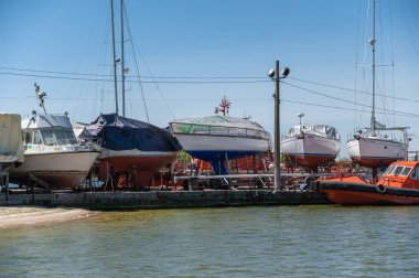 Turuncu bir pilot teknesi iskeleye demirlemiş. İskele boyunca kaygan yola bir grup yat monte edildi. Ukrayna, Mykolaiv -05 07 2022