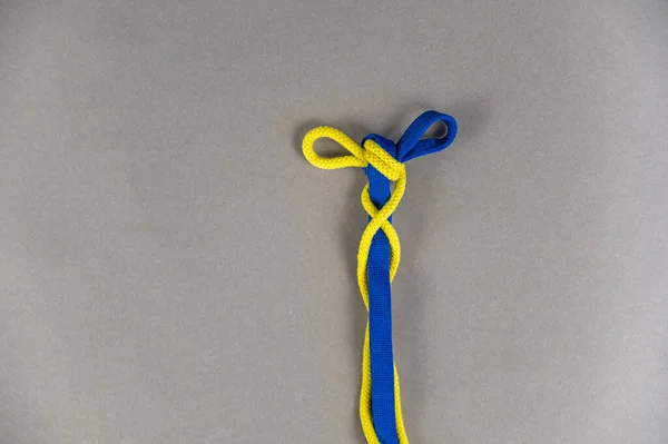 Многоцветные Шнурки Сером Фоне Два Шнурка Завязаны Узлом Синий Желтый — стоковое фото