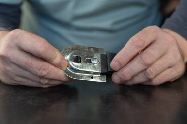 Yetişkin bir erkek, sürgülü dolap sistemi için en iyi paten kayışını tutuyor. Sürgülü kapılar için ayarlanabilir montaj plakası. Mobilya donanımı. Yakın plan. Seçici odak.