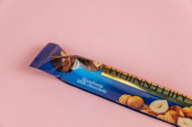 Pembe arka planın karşısında çikolata var. Milenyum Altın Ceviz Çikolatalı Süt ve tam fındık. Ukrayna, Mykolayiv -05 25 2022