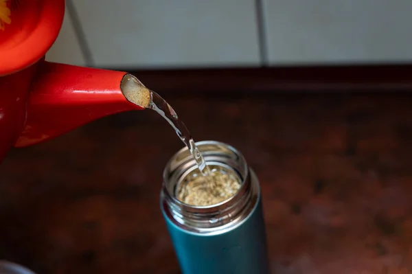 从红灯笼中沸腾的水倒入一个热水瓶中 茶壶里塞满了药草 干燥的花 有选择的重点 系列部分 — 图库照片