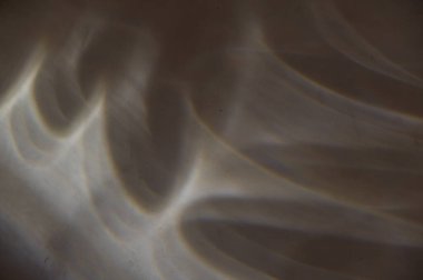 Karanlık bir taş duvardaki kıvrımlı güneş ışığı çizgileri. Farklı şekillerde ışık şekilleri ve çizgiler. Gri alçılı duvar. Farklı tasarım görevleri için soyut çoklu görev geçmişi. Seçici odak.