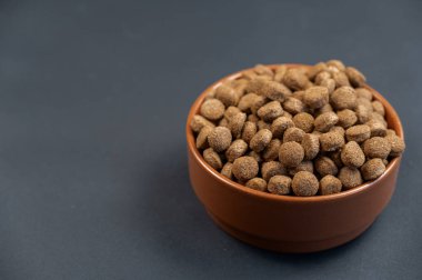 Gri arka planda bir kase köpek maması. Seramik kasede yuvarlak kahverengi topaklar. Kısırlaştırılmış ve sıkıştırılmış hayvanlar için yiyecek. Sağlıklı yiyecekler. Yukarıdan açılı görüş. Metin ve tasarım ögeleri için boşluk kopyala