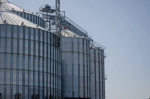 Construction of new cylindrical silos for grain storage. Metal silos are made of corrugated metal. A row of hand winches lifts the metal structure upward. Agribusiness. Grain exports.