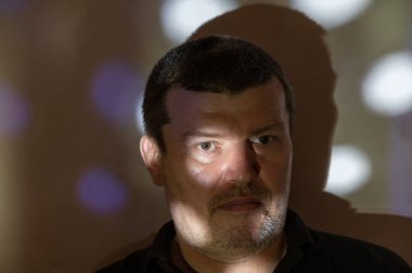 Duvara dayanmış yorgun bir adamın portresi. Işık huzmesi sağ gözünün etrafını aydınlatır. Orta yaşlı, kısa gri saçlı bir erkek. Adamın sırtı duvara dönük. İnsanlar, duygu konsepti.