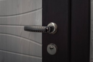 Kapı tokmağı. Krom kapı kolu beyaz ve kahverengi ön kapıda. Yakın plan. Seçici odak.