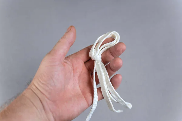 Homem Segurando Cordão Branco Mão Fundo Cinzento Cadarço Liso Com — Fotografia de Stock