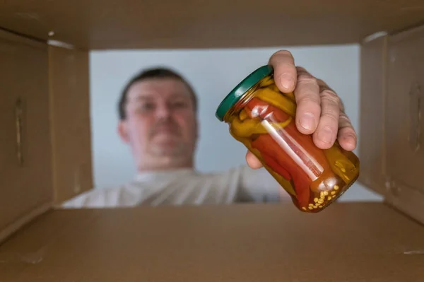 Homem Tira Comida Uma Caixa Papelão Legumes Enlatados Frasco Vidro — Fotografia de Stock