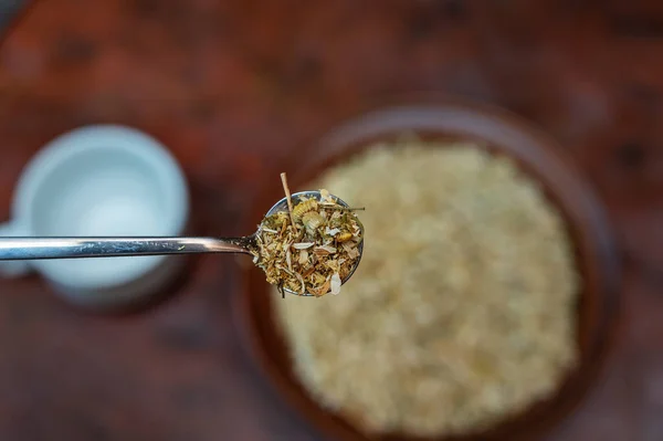在厨房桌子上方放满了一勺干菊花 背景上的褐色药草碗模糊不清 草药茶的制作过程或注入甘菊的过程 — 图库照片