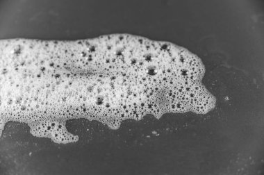 Renkli arka planda sabun köpüğü. Gri yüzeyde beyaz deterjan köpüğü kabarcıkları. Şampuan köpüğü dokusu. Seçici odak.