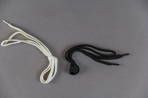 Два Плоских Шнурка Сером Фоне Белое Черное Шнурки Петлей Узлом — стоковое фото