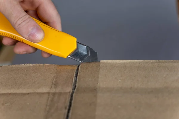 Man Hand Opens Cardboard Box Yellow Cutter Flaps Package Sealed — ストック写真