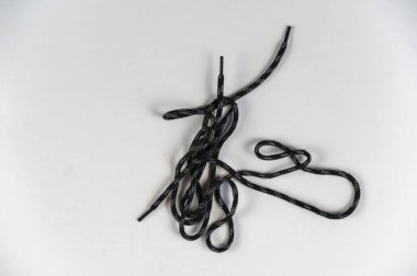 Tarafsız bir zemine karşı yuvarlak bir halat. Düğümlü gri ve siyah dantel. Yakın plan. Seçici odak.