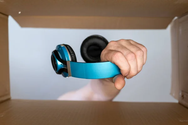 Man Hand Puts Headphones Cardboard Moving Box Wireless Stereophonic Device — Foto Stock
