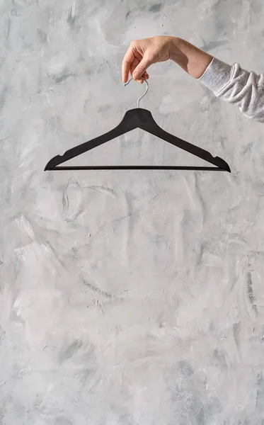 Çatı katındaki kaba alçının arka planında askı olan bir kadın eli. Moda stilisti ya da alışverişçi minimalist konsepti. Mağazalarda giyecek ya da satacak bir şey yok. Moda blog afişi şablonu