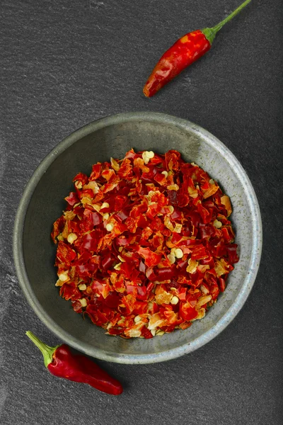 Crashed red spicy pepper on black stone. — Stock Photo, Image