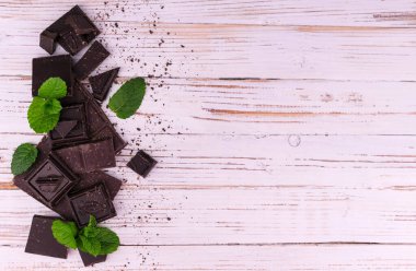 Beyaz ahşap arka planda yeşil naneli acı siyah çikolata parçaları. Düz lei. Boşluğu kopyala.