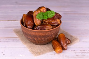 Beyaz ahşap arka planda, derin bir klozetin içindeki tatlı hurmalar..