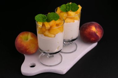 Siyah arka planda şeftalili iki bardak yoğurt..