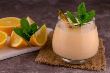 A glass of fresh orange smoothie.\nClose-up .