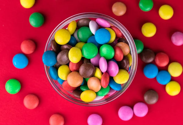 Veelkleurige Snoepjes Een Schaal Een Felrode Achtergrond Bovenaanzicht — Stockfoto