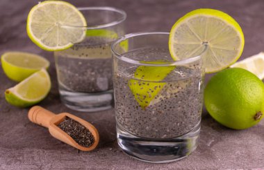  Gri zemin üzerinde kireç ve chia tohumları olan su.