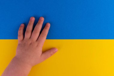 Ukrayna bayrağının arkasındaki küçük bir çocuğun eli. Ukrayna 'daki savaşa karşı kavram. Uzayı kopyala..