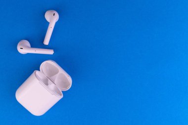 Mavi arka planı şarj edilmiş modern kablosuz bluetooth kulaklıklar..