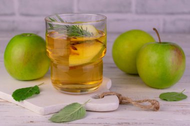 Elma suyu yeşil elmalardan beyaz tahta bir bardakta.