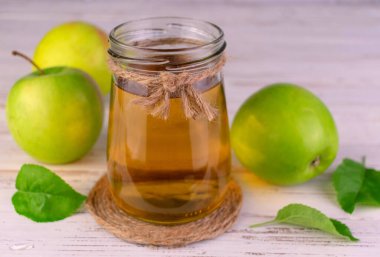 Beyaz arka planda cam bir kavanozda elma suyu. Yakın plan..