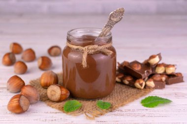 Çikolatalı kavanoz fındıklı beyaz ahşap arka planda. Yakın plan..