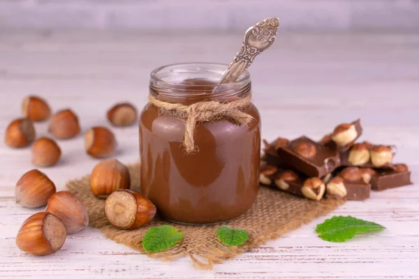 Çikolatalı kavanoz fındıklı beyaz ahşap arka planda. Yakın plan..