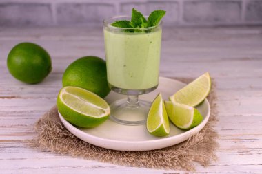 Beyaz ahşap arka planda bir bardakta limon naneli smoothie..