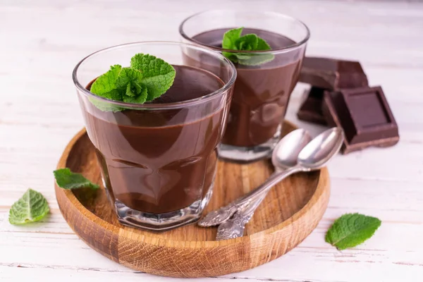 Chocolate pudding with mint glass on a wooden tray.