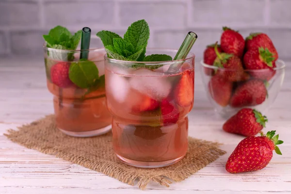 Naneli çilekli mojito ve beyaz ahşap bir masada buzlu bardaklar..