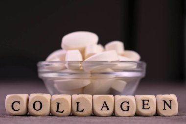 Kolajen tabletleri ve koyu arkaplandaki yazıt kolajeni.