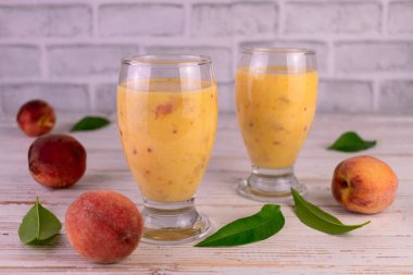 Beyaz arka planda viski bardaklarıyla taze organik şeftali suyu..