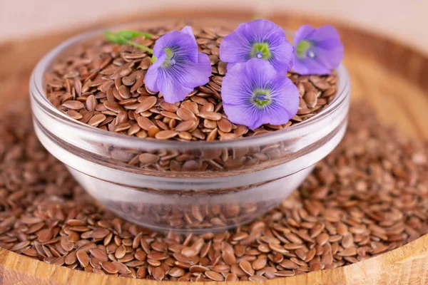 Useful flax seeds in a glass bowl and flax flowers.Close-up.