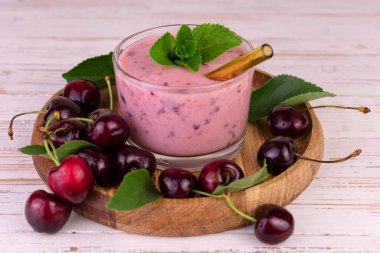 Tahta tepside bardakta taze vişneli smoothie..