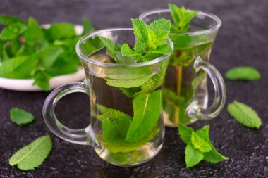 Siyah arka planda şeffaf bardaklarda naneli çay.