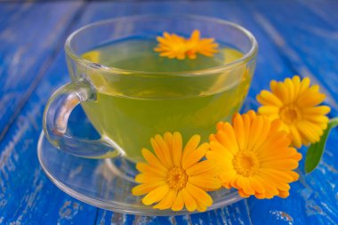 Mavi arka planda şeffaf bir fincanda takvim çayı. Yakın plan..